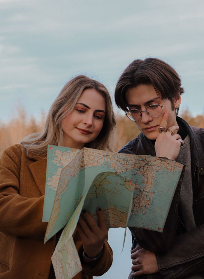 Young man and woman exploring countryside with a map, planning their next adventure.